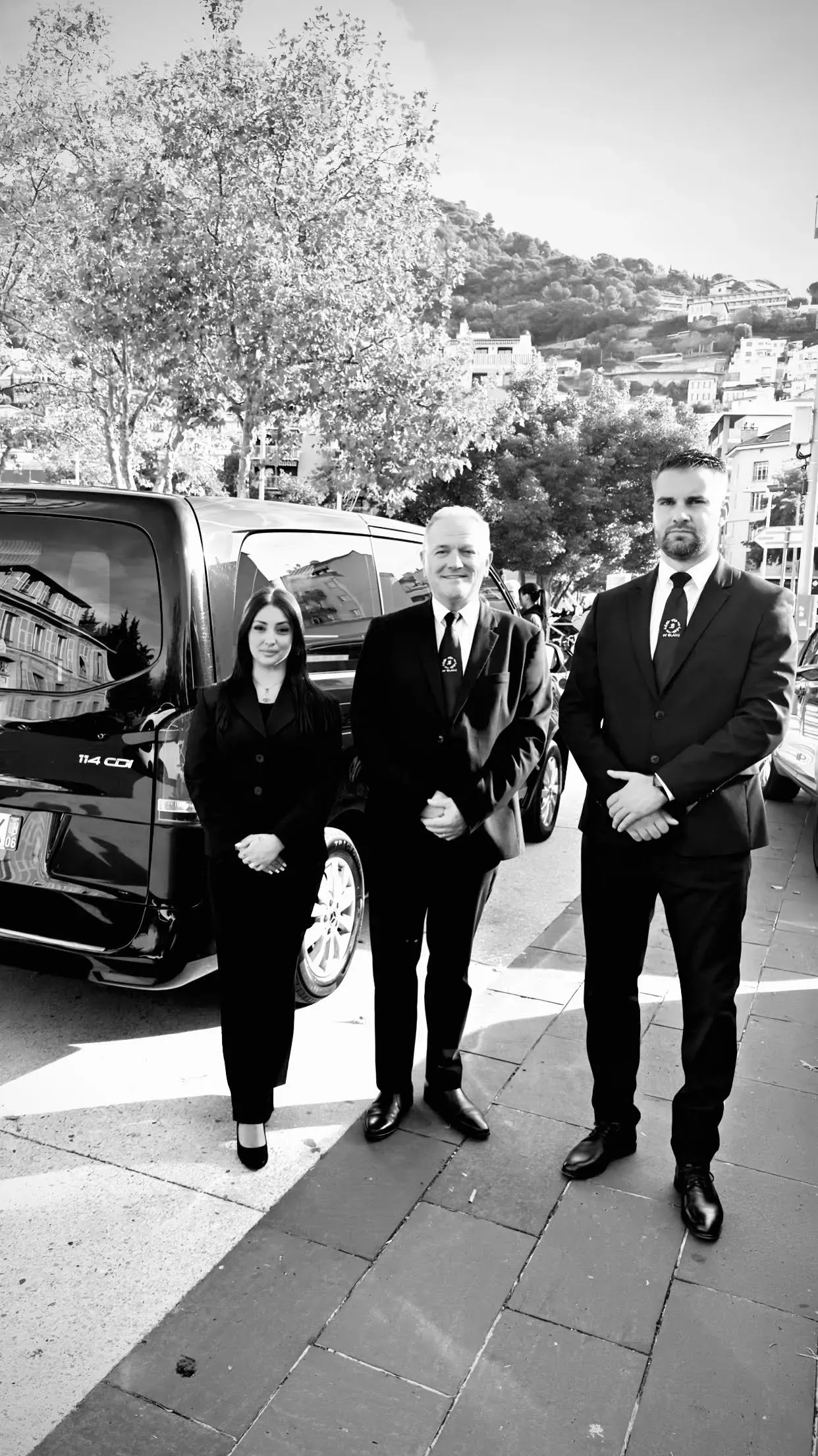 Équipe de pompes funèbres en costume sombre posant près d'un van.