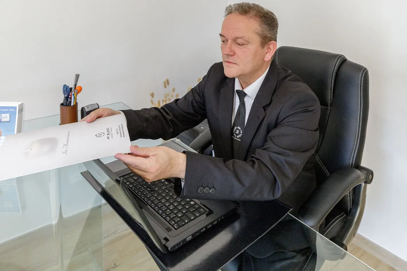 Conseiller funéraire PF Blanc présentant un dossier de prévoyance obsèques.